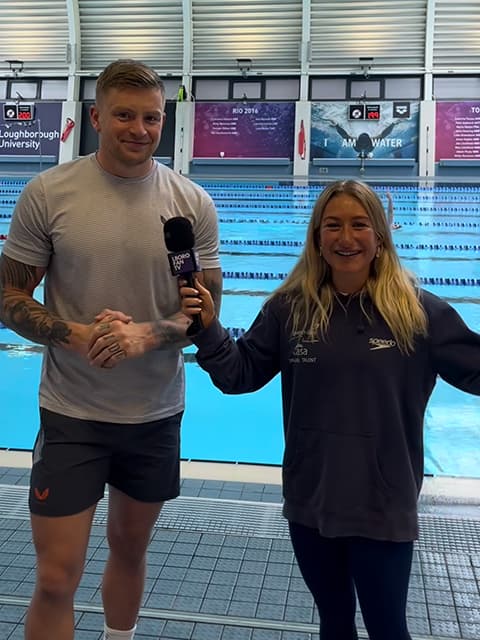 Adam Peaty with Bella Harris-Johnstone, standing by a swimming pool.