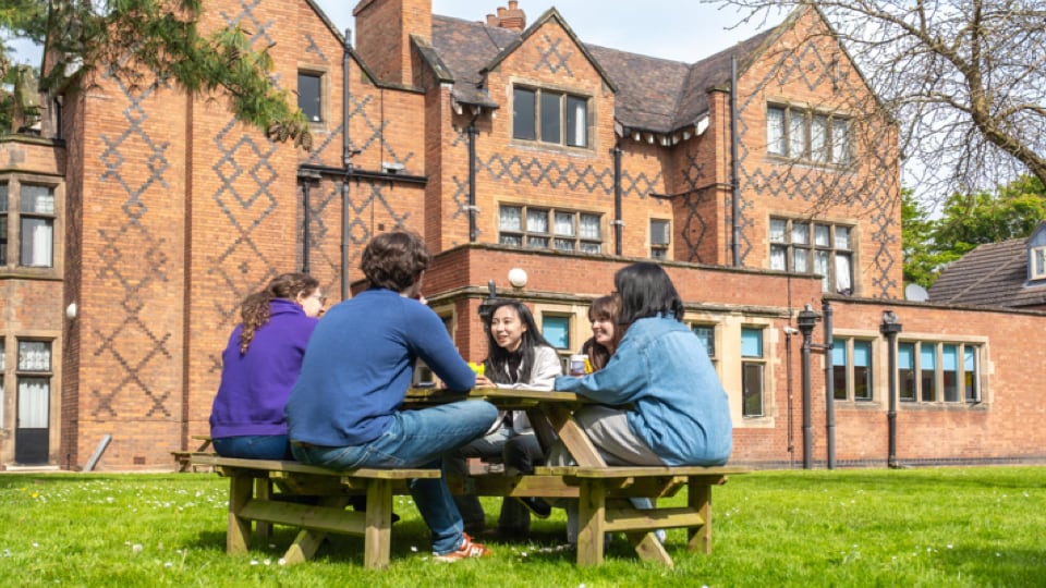 A group of students sitting on a picnic bench outside of their hall of residence
