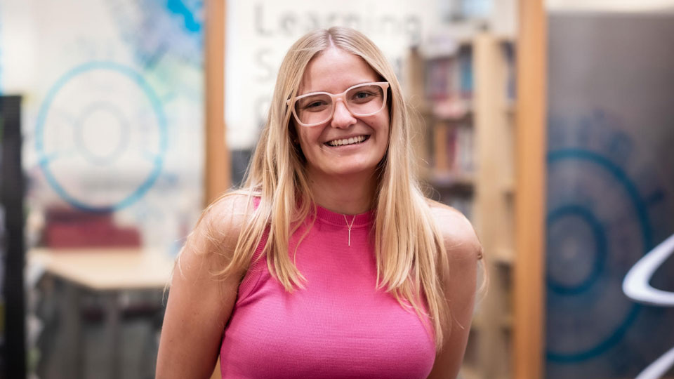 A female student smiling at the camera outside the maths learning support centre