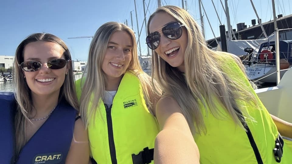 BSc Management student, Izzy Sims sat on a boat with two friends.