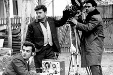 a camera operator, sound recordist and director standing together