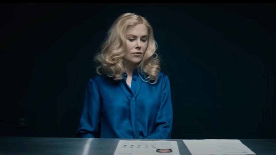 Nicole kidman sat at a desk in a dark room