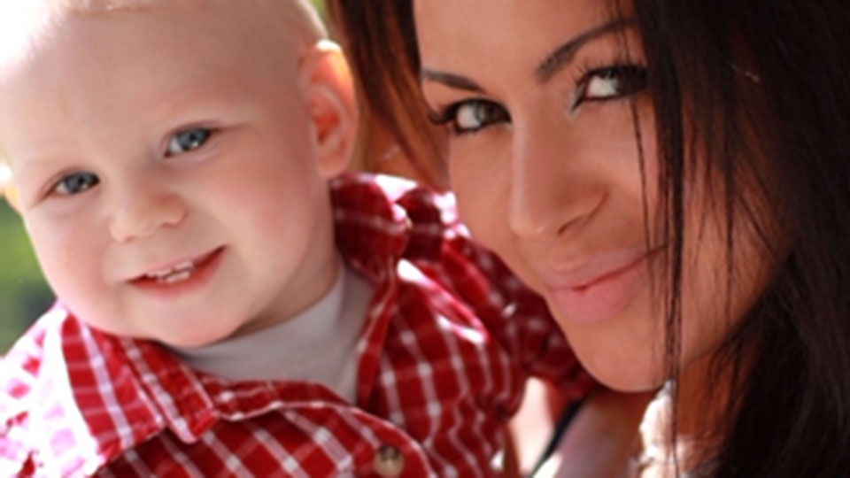 A woman holding a child in a red checked shirt