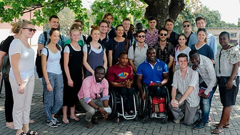 a group of people pose for a photo whilst standing under a tree