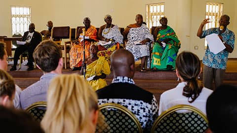 people seated listing to other people who are on a stage
