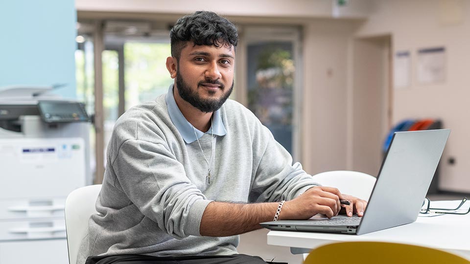 Jay sat at a table using a laptop