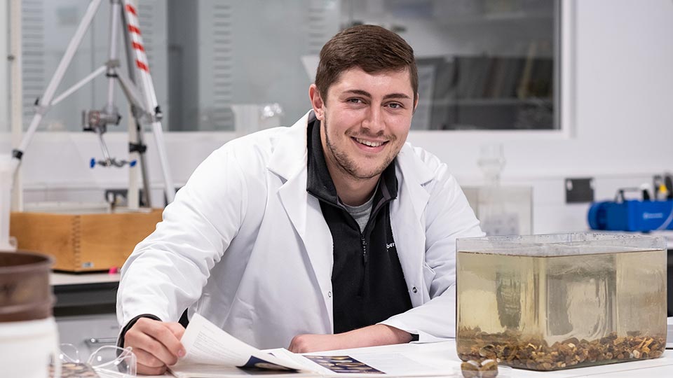 Kieran sat at a desk wearing a white lab coat