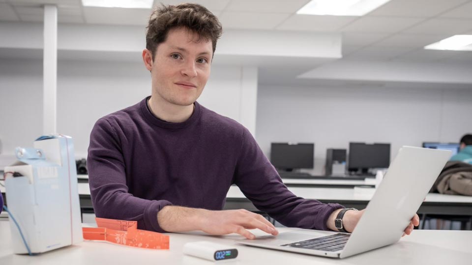 Thomas sat at a table using a laptop