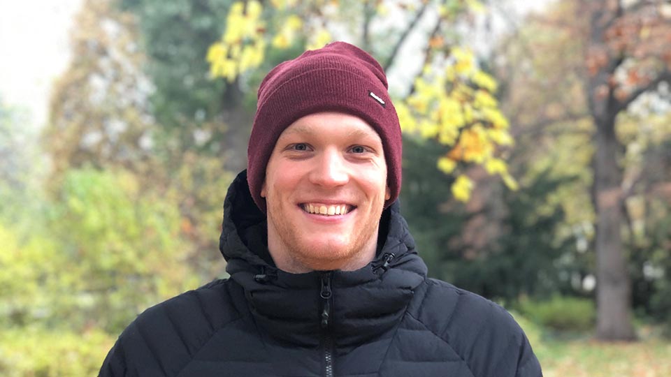 Felix stood outside wearing a winter hat and coat