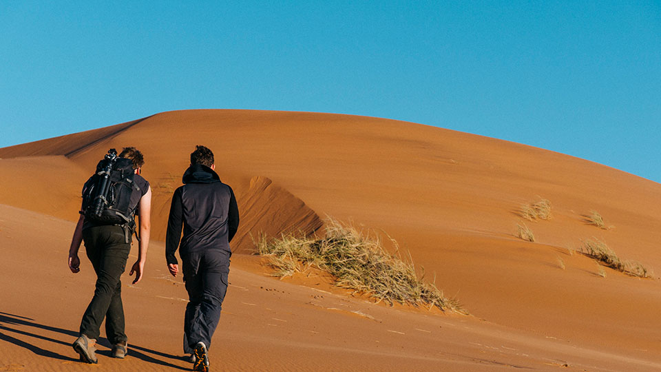 two people walking towards a dune in Namibia