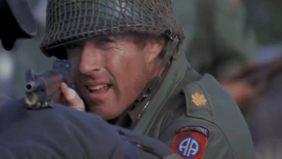 A man in miltary uniform pointing a gun