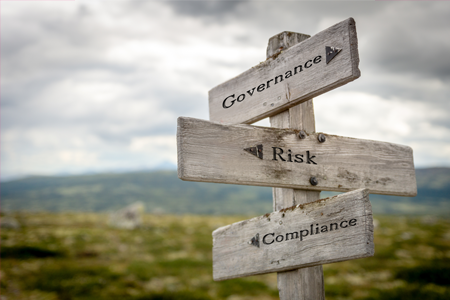 A wooden sign pointing to governance risk compliance