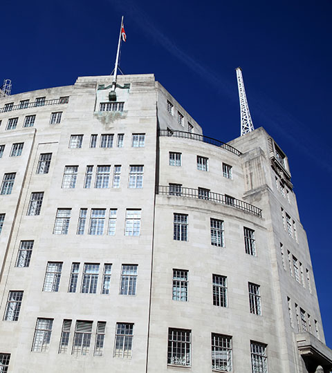 Large white building with a flag and radio mast on the roof