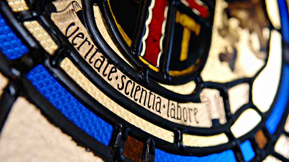 Stained glass bearing the Latin phrase 'veritate scientia labore', translating as 'the truth of knowledge is hard work' 