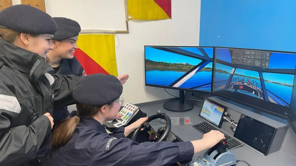Three sea cadets looking at and using their new ship simulator.
