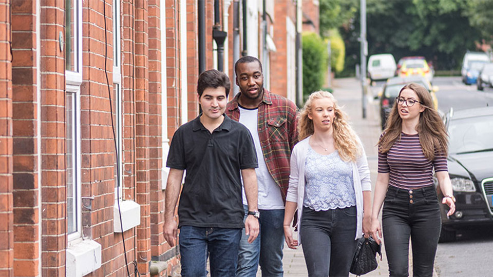 Four students walking along a residential street