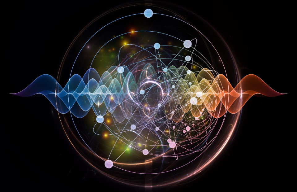 Concept image showing an atom and electrons surrounding it with wavelengths going through the middle. Rainbow-colour scheme on a black background