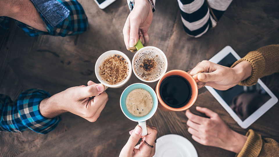 A group of people holding cups of tea and coffee together in a circle.