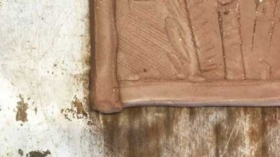 A clay tile set within a wooden frame, showcasing a blend of natural materials and craftsmanship.