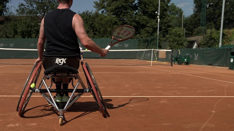 a wheelchair tennis player playing a shot from the baseline