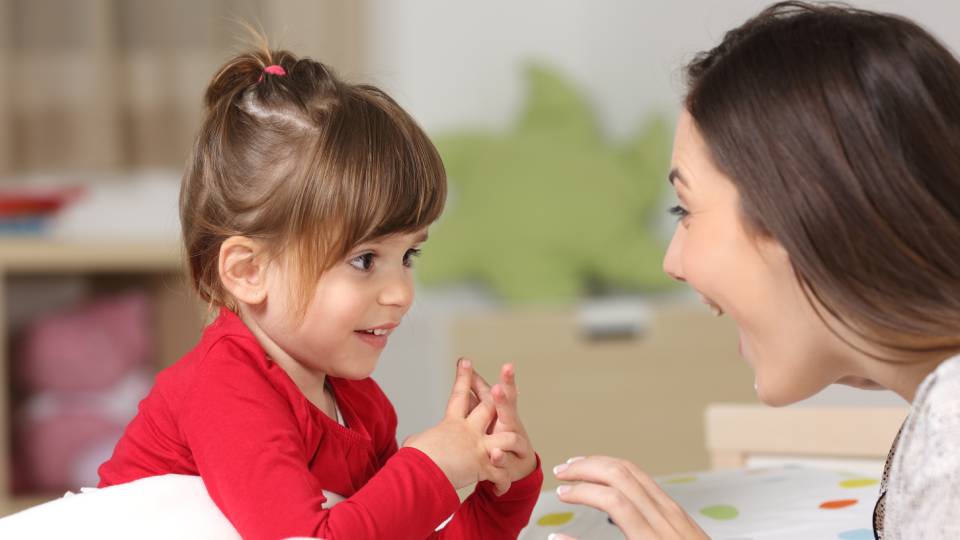 a child and woman smile at each other