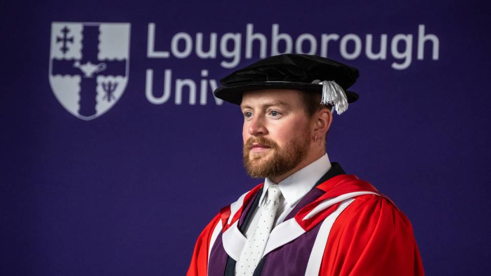 Adam Peaty dressed in his honorary graduate gown looks off camera