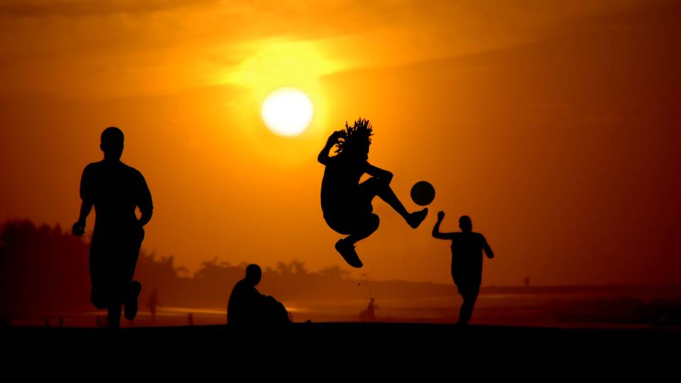 shadows of people playing football in the sunset