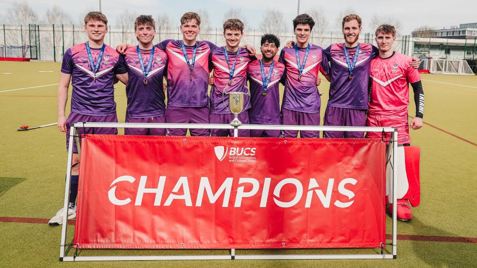 athletes with a cup behind a champions stand