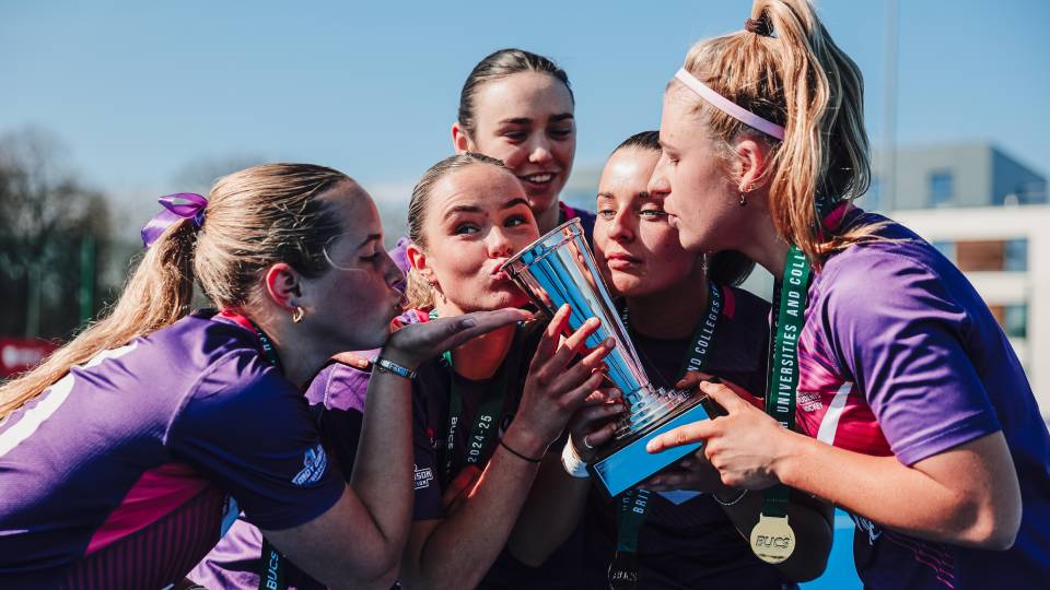 athletes gather round to lift a trophy