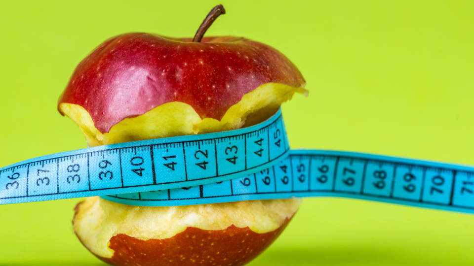 A half eaten apple wrapped in a measurement tape