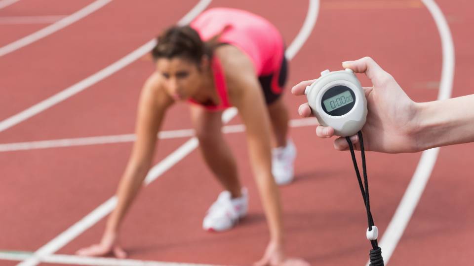 an athlete on the starting blocks with a coach timing them