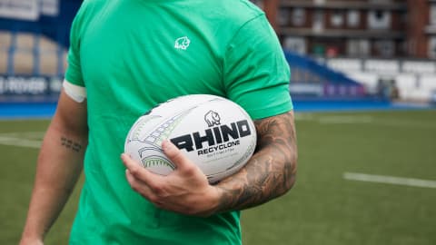 a man in a green t-shirt holding a rugby ball