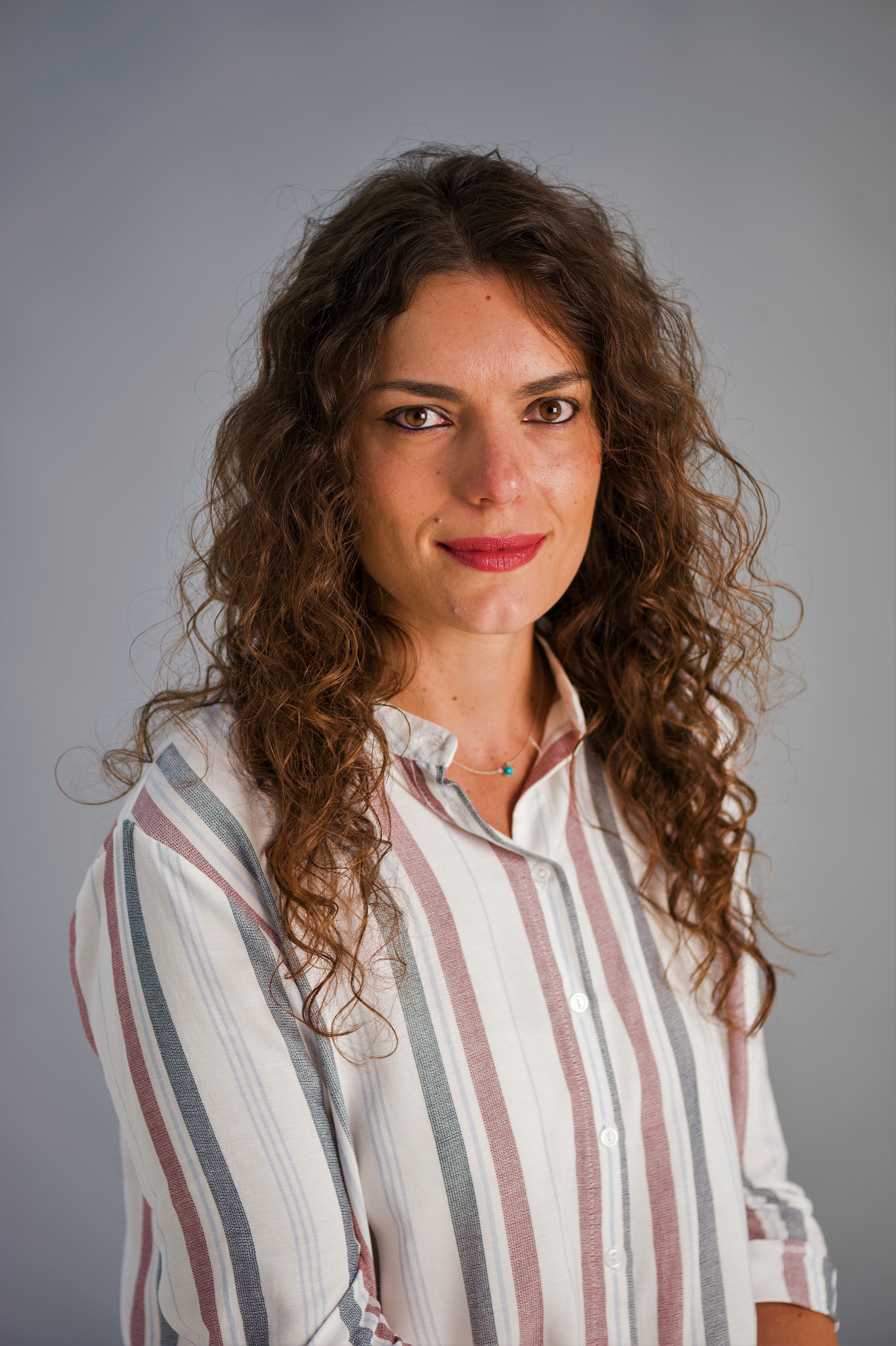 Headshot of Dr Pacella who is facing the camera and wearing a patterned shirt against a grey background