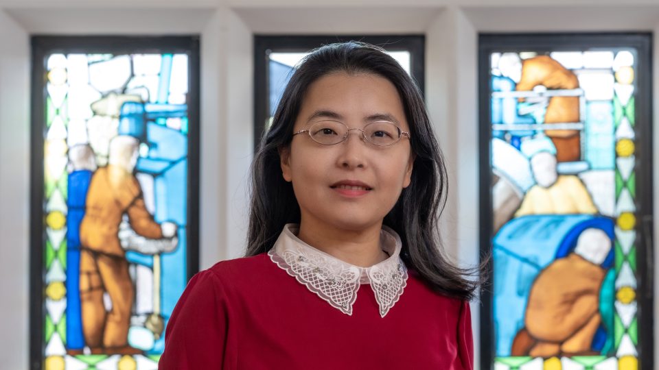 Close-up of Diwei Zhou in front of stained glass windows.