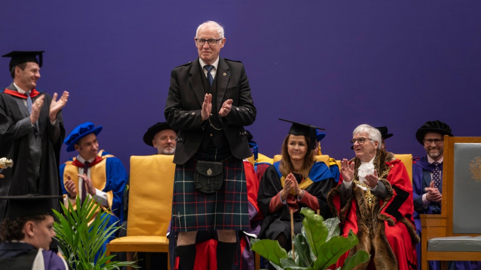 Eric stood on stage during the graduation ceremony clapping as he receives his University medal