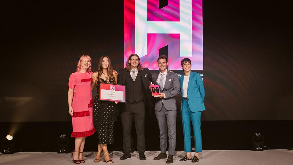 Five people standing on stage holding a trophy and a certificate at the HEIST Awards ceremony.