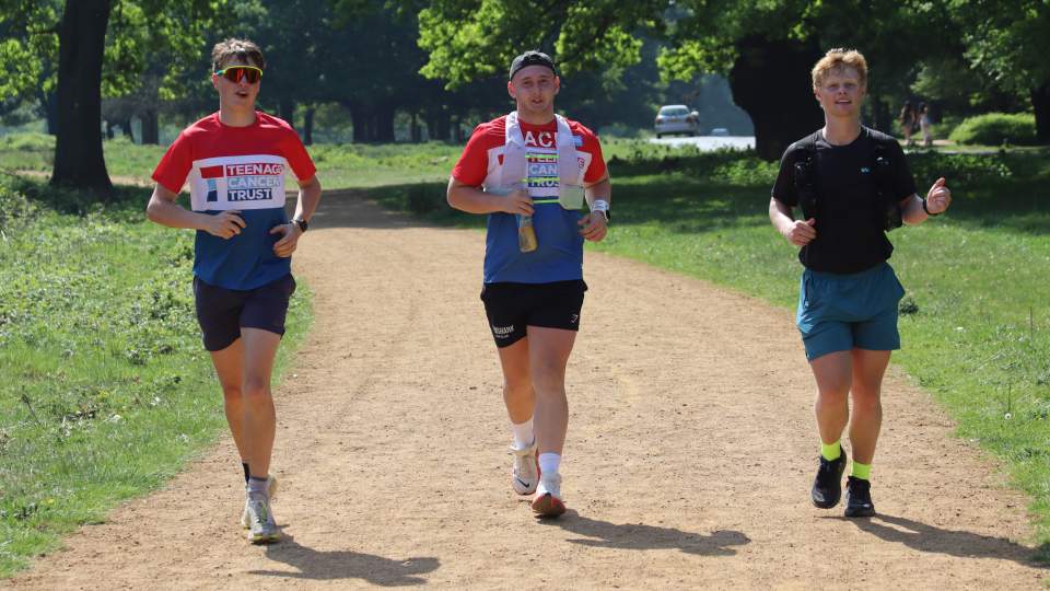 Three students running alongside each other on a path.