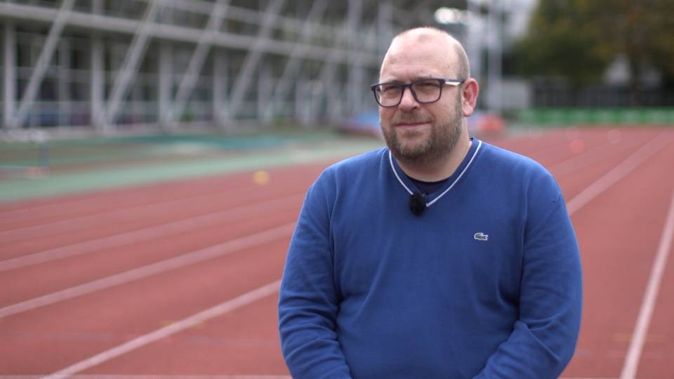 a man sat down with a running track in the background