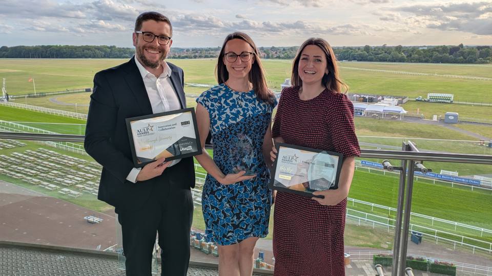 Three staff members from the Legal Services team stood together outside smiling at the camera whilst holding the AULP awards they have won
