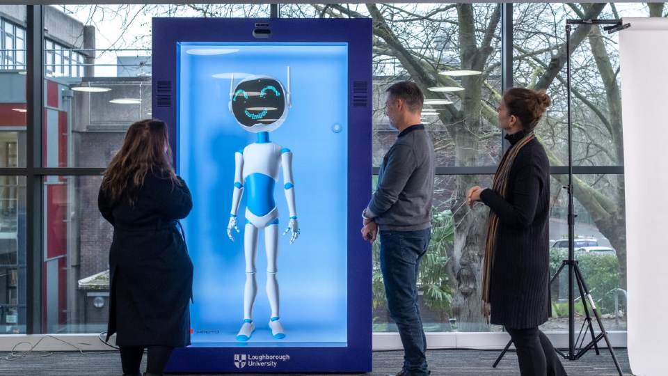 The Proto Hologram inside a room showing a robot avatar on its screen, with people stood next to the proto hologram watching it