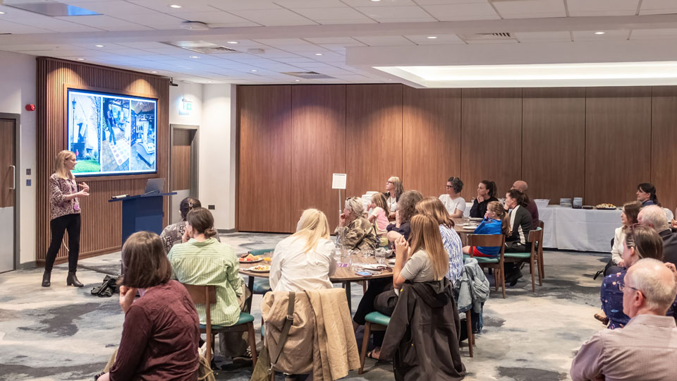 A group of people seated at tables in a well-lit room, engaged in conversation and collaboration.