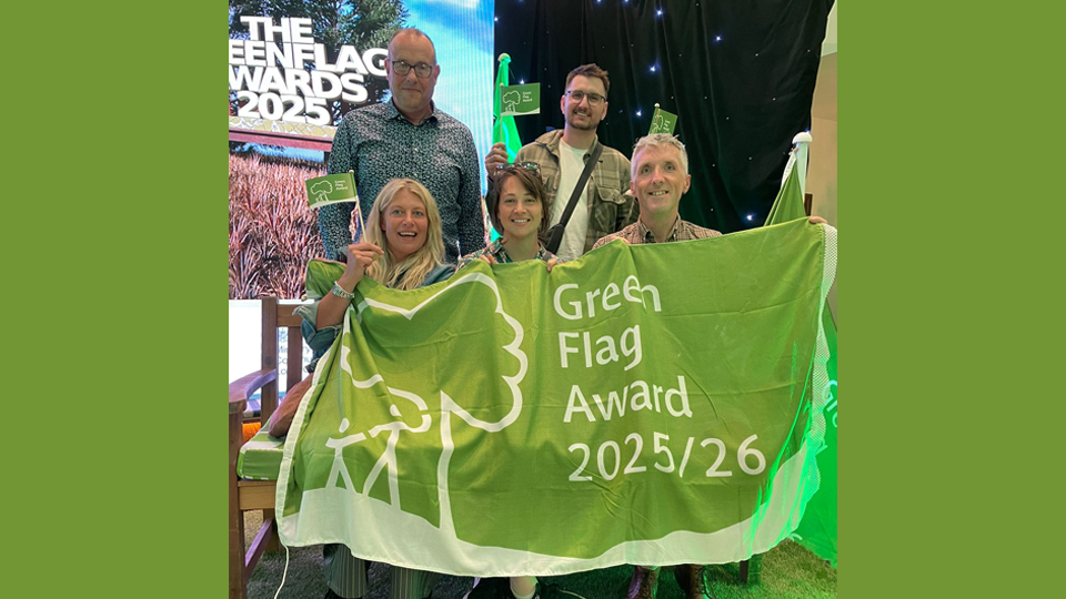 Green flag award winners proudly display their certificates at a recognition event, celebrating their achievements in sustainability.