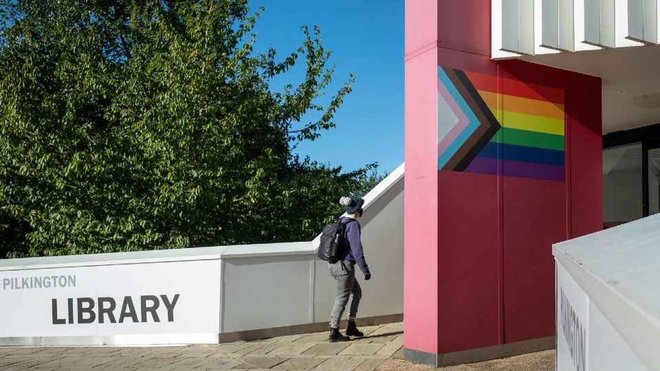 A student walking into the Pilkington Library.