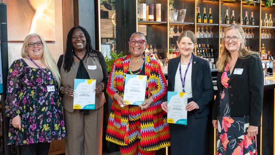 Five women standing together holding Maia certificates.