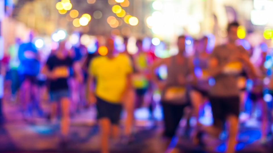 A group of runners at nighttime wearing reflective clothing.