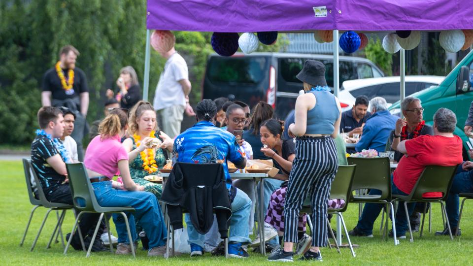 Staff and students sat together outside at a table eating food and chatting