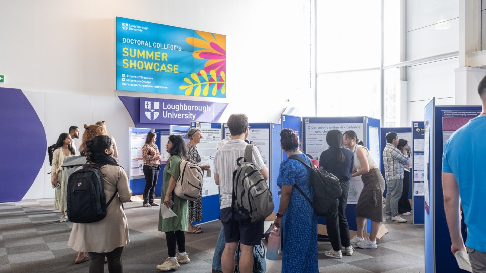 A group of people stand in a spacious room with various posters on the walls.