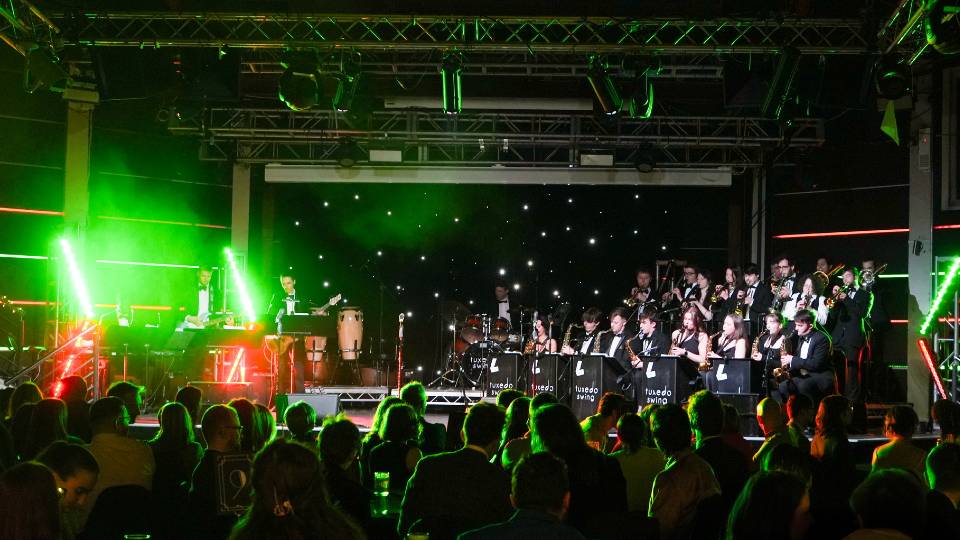 Tuxedo Swing band playing on stage in front of an audience.
